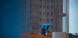 builder laying bricks on wall