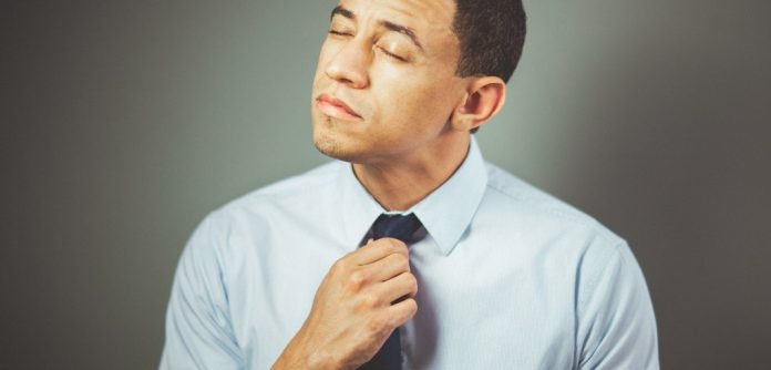 man adjusting tie looking uncomfortable