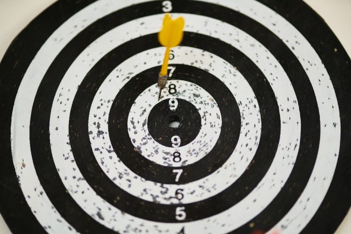 black and white dartboard with dart missing bullseye
