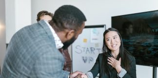 man shaking womans hand thanking her with colleague looking on