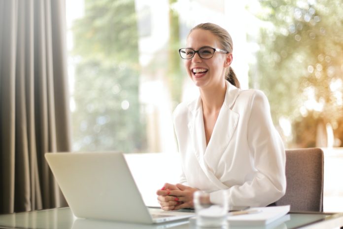 lady in white shirt sitting at laptop, smiling widely