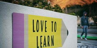 man walking past building that has sign that says "love to learn"