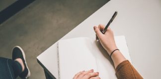 person wiriting in notebook