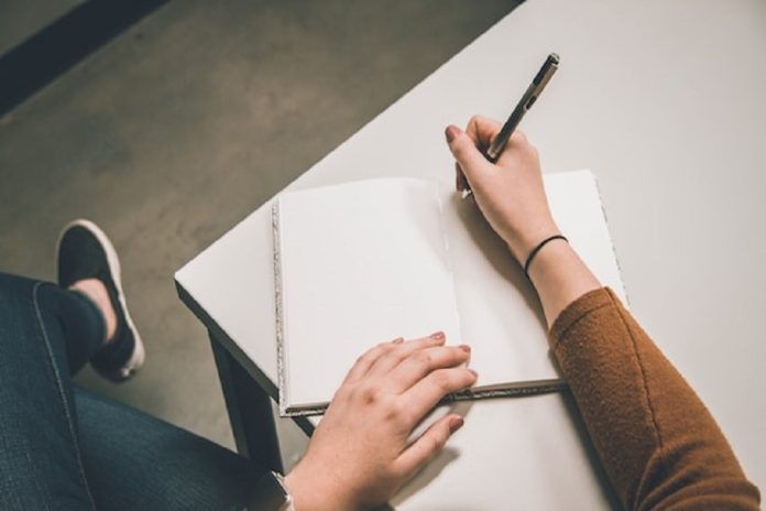 person wiriting in notebook