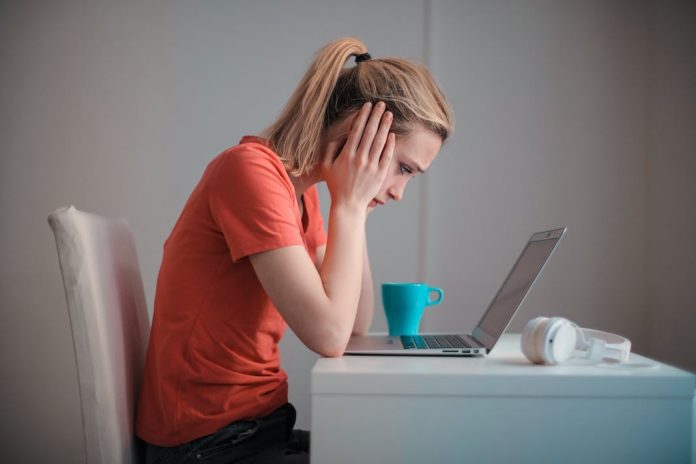 lady with head in her hands staring blankly at laptop