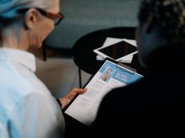 lady with glasses reviewing another ladies cv on a clipboard