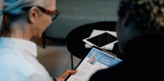 lady with glasses reviewing another ladies cv on a clipboard